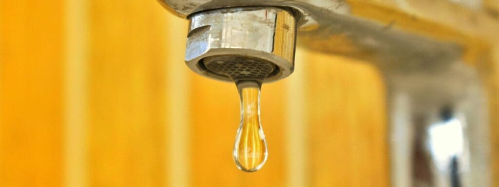 stainless steel faucet with hard water stains dripping water