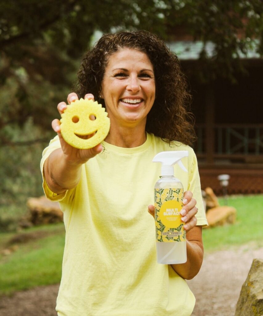 Woman in yellow Lemon Fresh cleaners shirt holding a sponge