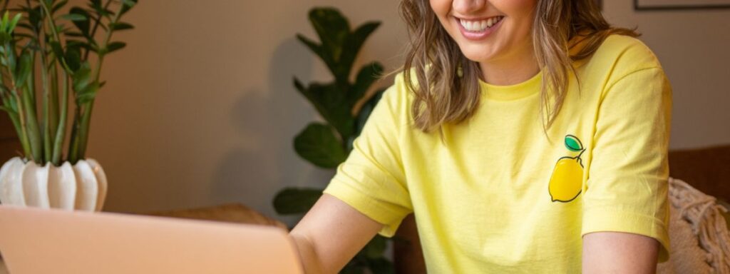 Katlin Knutson, SLC Cleaning Company owner, working at a laptop wearing a yellow Lemon Fresh Cleaners shirt