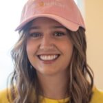 Woman smiling wearing a pink hat that says lemon fresh cleaners